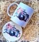 Preview: Tasse und runder Untersetzer mit Kamera- und Blumenmotiv im Aquarellstil, dekorativ in Holzwolle verpackt.